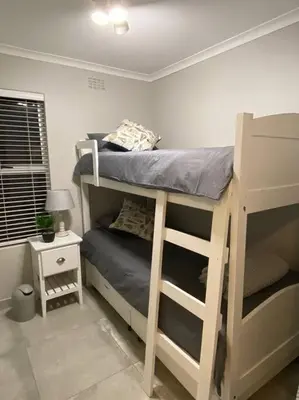 a bedroom with two bunk beds and a night stand at Huis by die See in Hermanus
