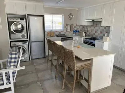 a kitchen with a island with chairs and a refrigerator at Huis by die See in Hermanus