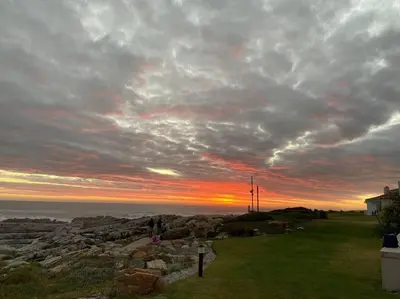 a sunset over the ocean with a cloudy sky at Huis by die See in Hermanus