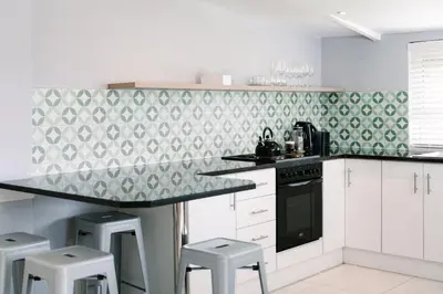 a kitchen with white cabinets and a green and white wallpaper at The Salene Hotel & Apartments in Stellenbosch
