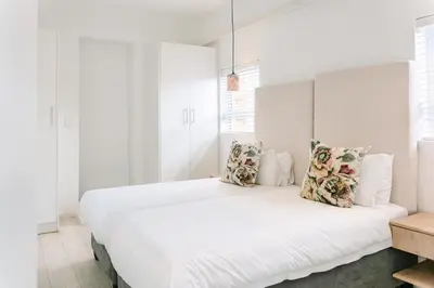 a white bedroom with a large white bed with pillows at The Salene Hotel & Apartments in Stellenbosch