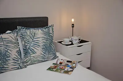 a bedroom with a bed with pillows and a night stand at Aloe Aloe Cottage in Cape Town