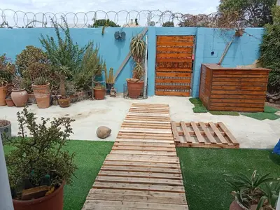 a garden with a wooden path and plants and a blue wall at Cozy Private En Suite Studio in Cape Town