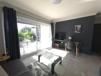 a living room with a large window and a table with chairs at 82 Steps to the Beach in Pringle Bay