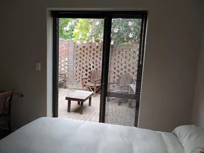 a bedroom with a bed and a view of a patio at TERRA NOVA ACCOMMODATION - Unit Esmé in Cape Town