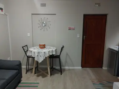 a living room with a table and chairs and a door at TERRA NOVA ACCOMMODATION - Unit Esmé in Cape Town
