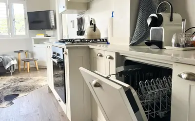a kitchen with white cabinets and a stove top oven at C'estÇa Cottage Modern Luxurious Sounds of the Sea in Hermanus