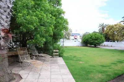 a group of chairs sitting on a patio next to a yard at sonsandsee in Hermanus