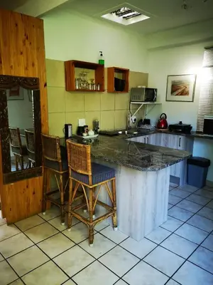 a kitchen with a large counter with chairs in it at Santika Garden Cottage Stellenbosch in Stellenbosch