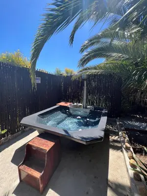 a hot tub in a yard next to a fence at Santika Garden Cottage Stellenbosch in Stellenbosch