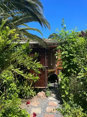 a garden with a chair in front of a house at Santika Garden Cottage Stellenbosch in Stellenbosch