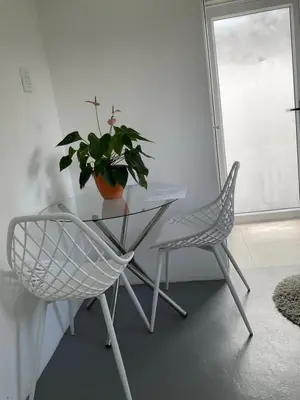 a white table and chair with a potted plant on it at Bird Song Cottage - Table View in Cape Town