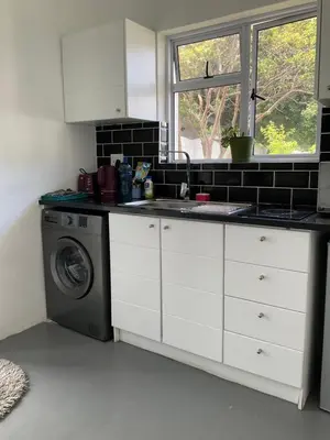 a kitchen with a sink and a washing machine at Bird Song Cottage - Table View in Cape Town