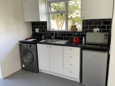 a kitchen with a sink and a washing machine at Bird Song Cottage - Table View in Cape Town