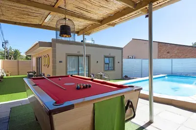 a pool table in a yard next to a swimming pool at Marigold in Brackenfell