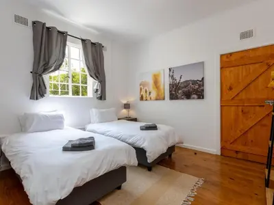 a bedroom with two beds and a wooden door at Jonkershoek Valley Cottage in Stellenbosch