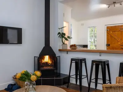 a fireplace in a living room with stools and a table at Jonkershoek Valley Cottage in Stellenbosch