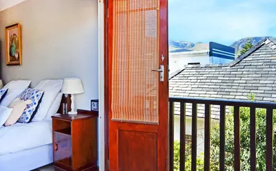 a door leading to a bedroom with a bed and a balcony at Chesham House in Hermanus