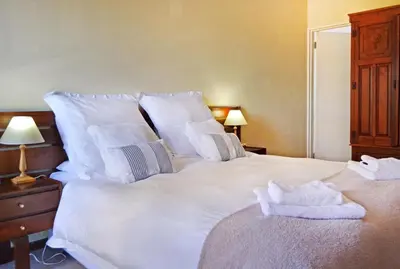 a large white bed with towels on top of it at Chesham House in Hermanus