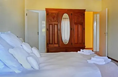 a bedroom with a white bed with white pillows at Chesham House in Hermanus