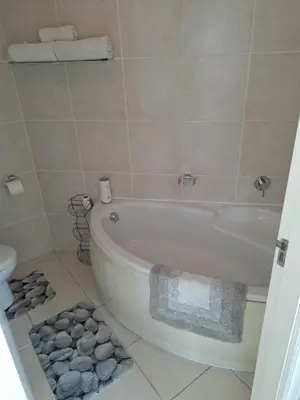 a bathroom with a bath tub and a pile of towels at Palmsbeach 3 in Strand