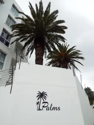 a palm tree in front of a white building at Palmsbeach 3 in Strand