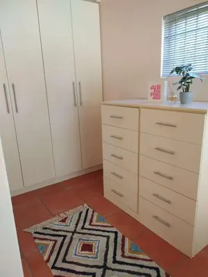a bedroom with white cabinets and a rug at Plattekloof Treasures in Cape Town