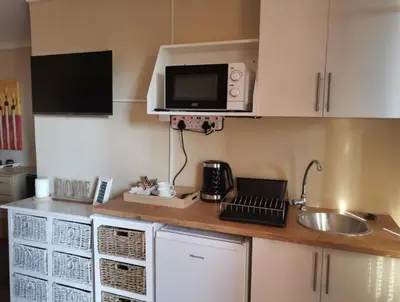 a kitchen with a counter with a sink and a microwave at Plattekloof Treasures in Cape Town