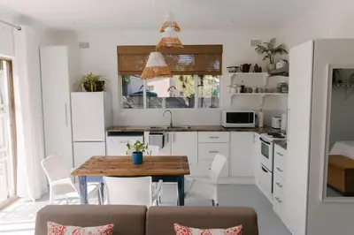 a kitchen with white cabinets and a wooden table at McLeod's & Stuart's Cottage in Somerset West