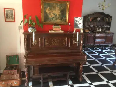 an old piano in a room with a red wall at Helderberg Guesthouse in Gordonʼs Bay
