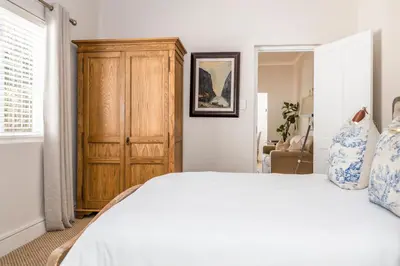 a bedroom with a bed and a wooden cabinet at Petit Ermitage in Franschhoek