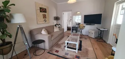 a living room with a couch and a tv at Petit Ermitage in Franschhoek