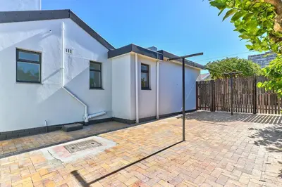 a white house with a fence and a brick patio at Family Home, WiFi, Patio, Secure Parking in Cape Town