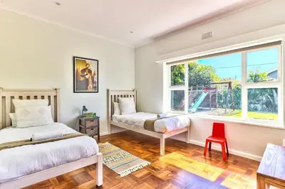 a bedroom with two beds and a red chair at Family Home, WiFi, Patio, Secure Parking in Cape Town