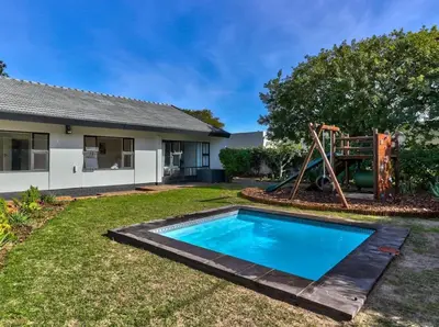 a backyard with a pool and a playground at Family Home, WiFi, Patio, Secure Parking in Cape Town