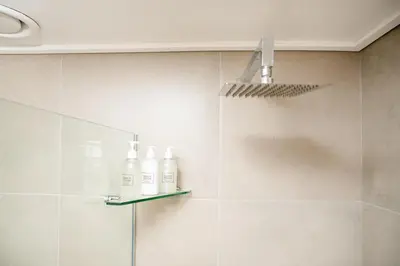 a bathroom with three bottles on a glass shelf at Beachfront 2 bed w swimming pool, Blouberg 54 Beach Break in Bloubergstrand