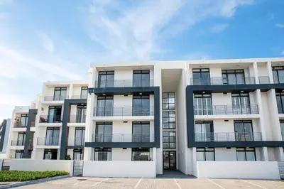 a white apartment building with black balconies at Beachfront 2 bed w swimming pool, Blouberg 54 Beach Break in Bloubergstrand