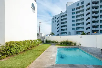 a swimming pool in front of a building at Beachfront 2 bed w swimming pool, Blouberg 54 Beach Break in Bloubergstrand