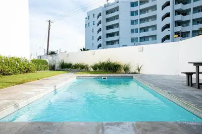 a swimming pool with blue water in front of a building at Beachfront 2 bed w swimming pool, Blouberg 54 Beach Break in Bloubergstrand