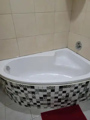 a bath tub in a bathroom with a tile wall at Jacmo Guest Private Rooms in Cape Town