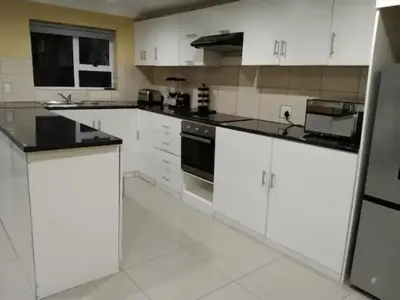 a kitchen with white cabinets and black appliances at Jacmo Guest Private Rooms in Cape Town