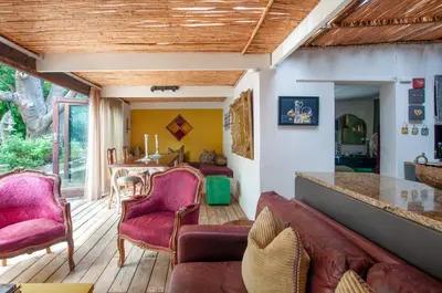 a living room with wooden floors and pink chairs at Art Box in Greyton