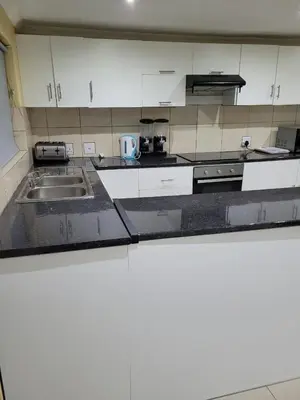 a kitchen with white cabinets and black counter tops at On the Wrench in Cape Town