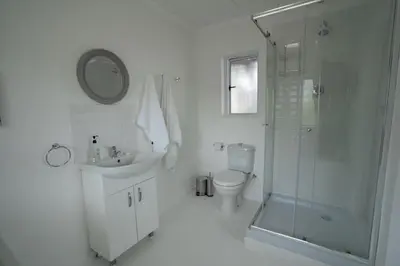 a white bathroom with a shower and a toilet and a sink at Stony Point Beach House in Clareport