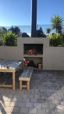 a picnic table and bench with a fire place at Boardrooms Kite Accommodation in Cape Town
