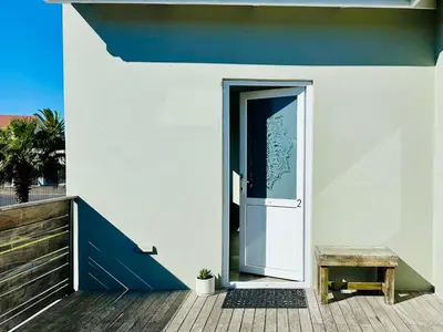 a door leading to a balcony with a bench at Boardrooms Kite Accommodation in Cape Town