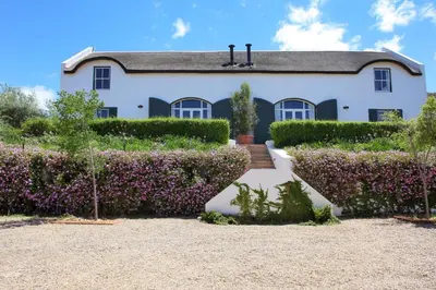 a white house with purple bushes in front of it at Penhill Farm East Grange in Nuy