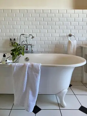 a white bath tub in a bathroom with white tiles at Penhill Farm The Manor House in Nuy