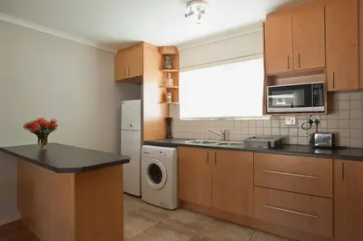 a kitchen with a sink and a washing machine at Sunbird Cottage in Somerset West