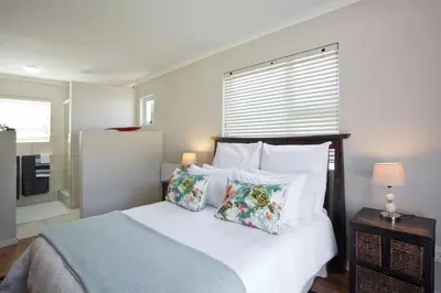 a bedroom with a bed with pillows and a window at Sunbird Cottage in Somerset West